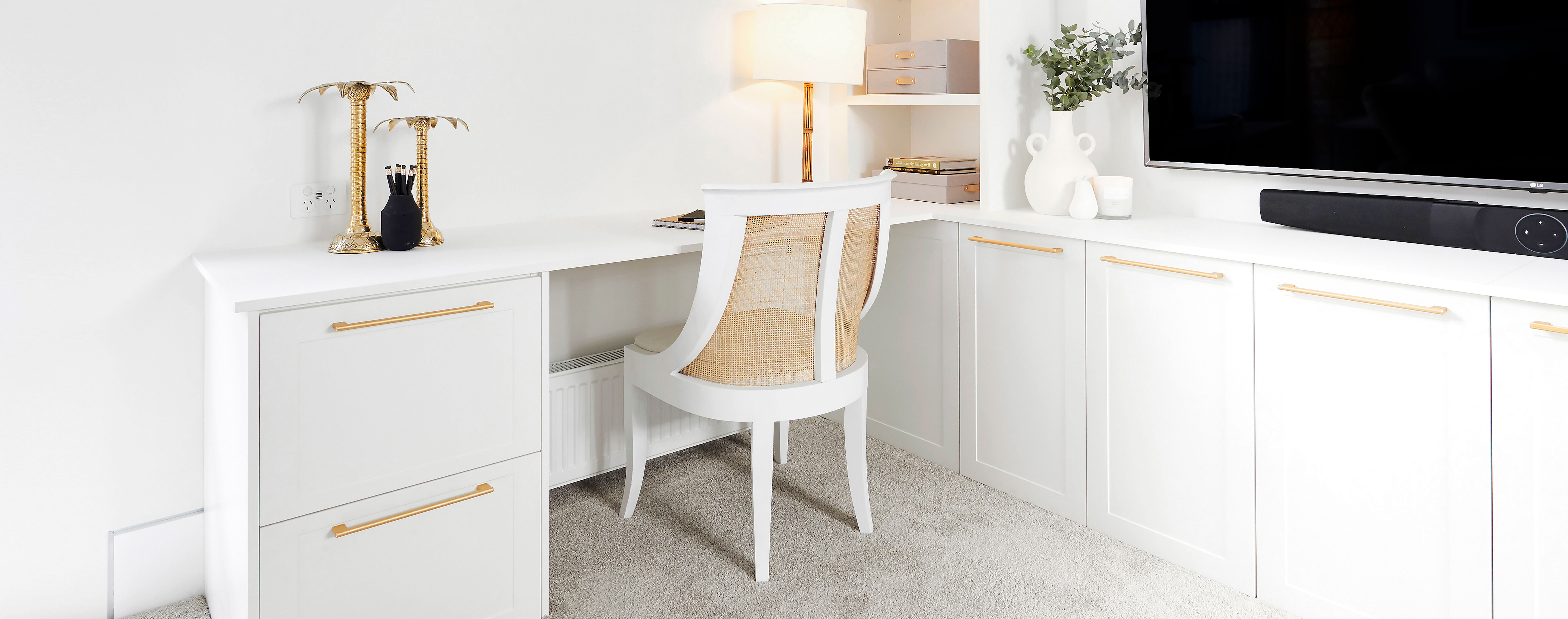 A white Hamptonsstyled home office with gold accents