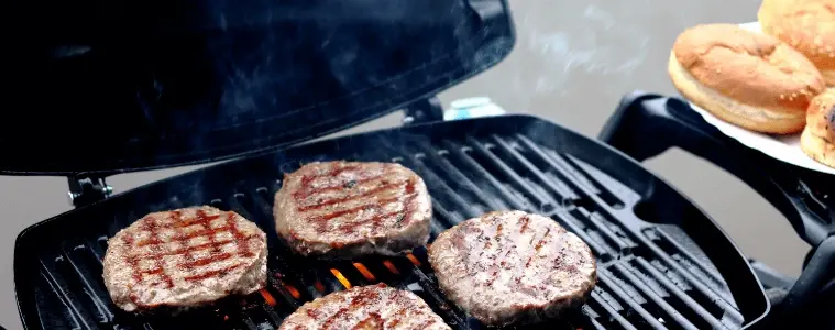 Closeup of burger pattys cooking on a Weber BBQ