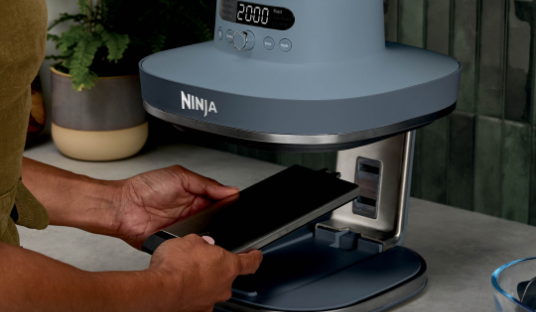 Image of a woman changing the adjustable base on a Ninja Crispi Pro Air Fryer