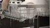 A person uses the handles on the side of the top rack to lower the basket in their LG QuadWash dishwasher.