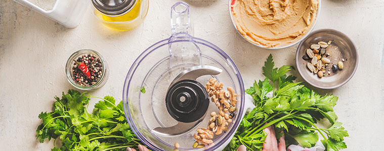 Mincing meat in a food processor with large tomatoes and lettuce in foreground