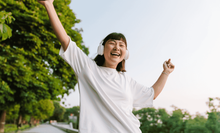 Woman listening to noise cancelling headphones outside in the sun 