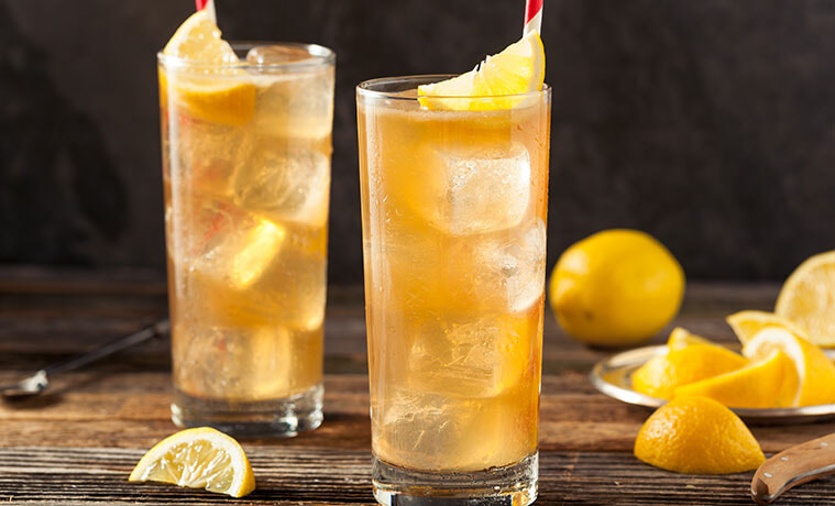 Citrusflavoured mocktails in tall glasses next to orange segments and oranges on a table 