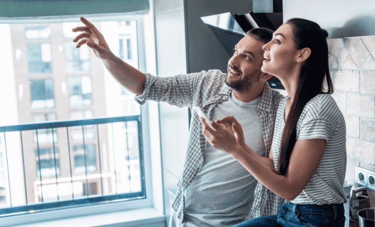 Man and a woman using their phone to turn on their lights in the kitchen 
