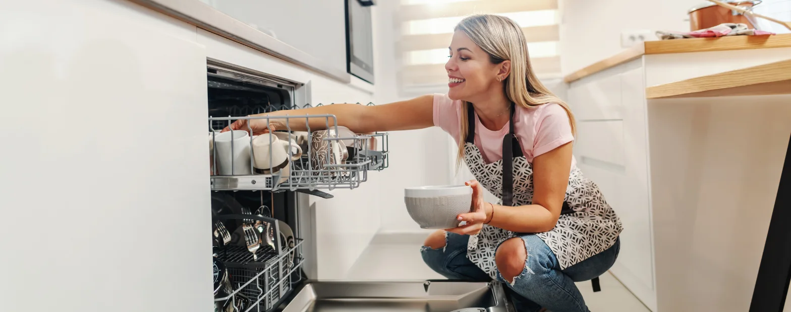 Lifestyle image of a woman loading a dishwasher in a modern kitchen