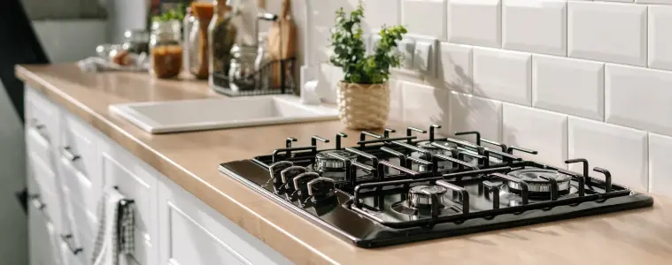 Black gas cooktop on timber countertop in modern kitchen.