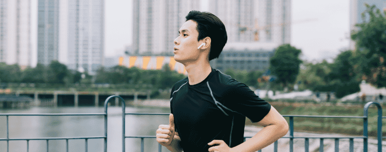 a man running along the water with earphones in 