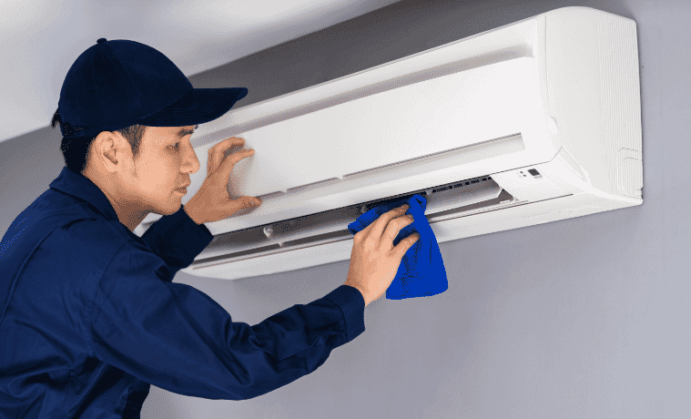 Man in navy shirt servicing an air conditioner