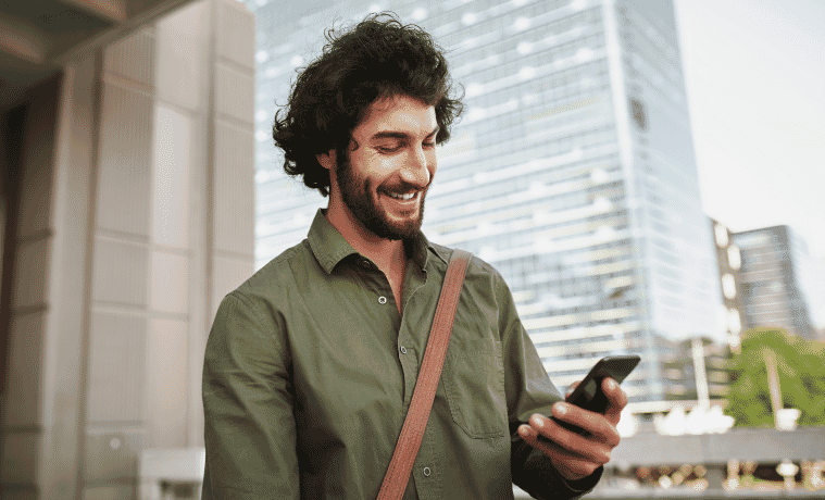 a man walking outside after work whilst looking at his mobile phone 