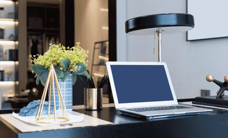 A laptop and elegant lamp on a desk in a modern study