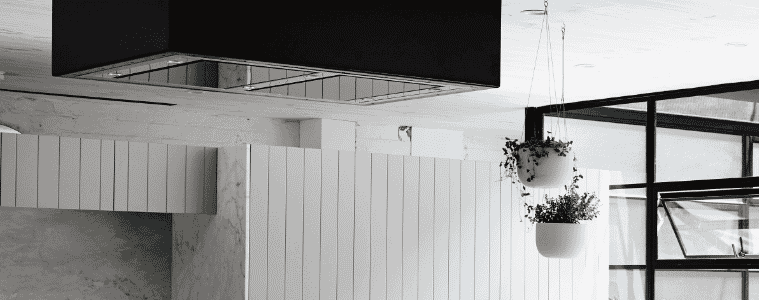 A black integrated rangehood in a white modern kitchen