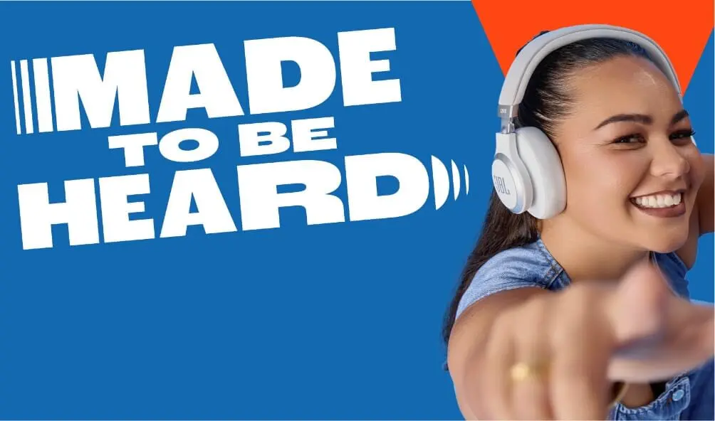 woman points at the camera wearing JBL headphones