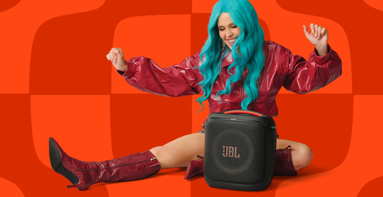 woman points at the camera wearing JBL headphones