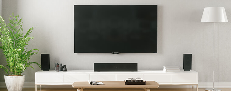 Modern living room with wallmounted big screen TV and soundbar and tower speakers 