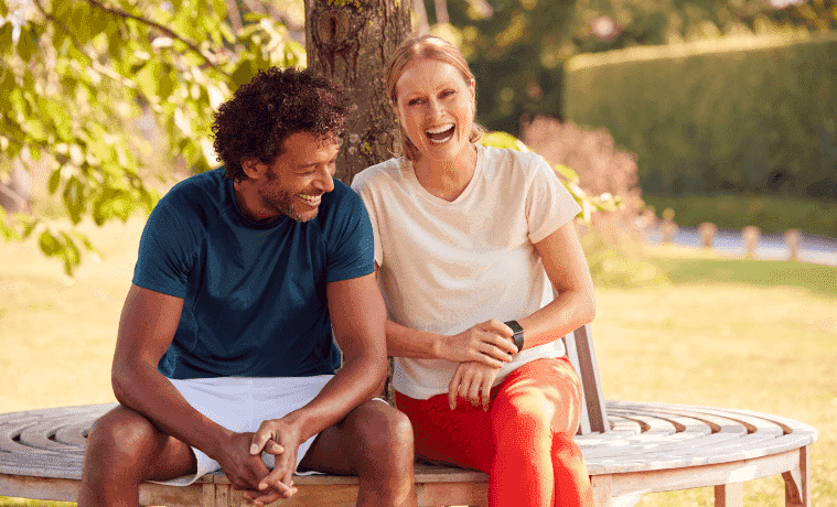 A man and woman in fitness clothing rest on a bench