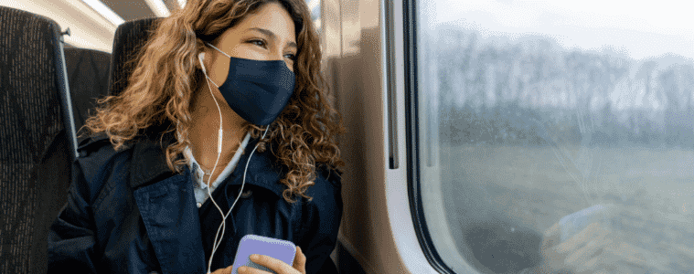 A woman wearing a mask sits on a bus
