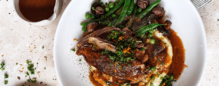 Plate of lamb on mash with greens and red wine gravy