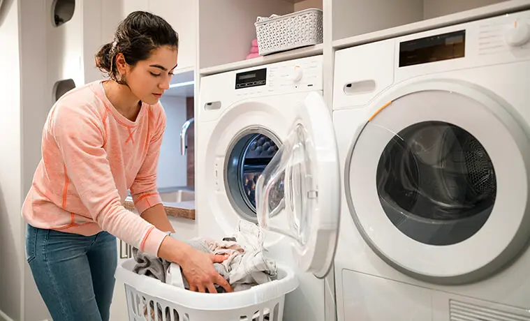 A woman unloads fresh laundry from her washing machine before placing it in the clothes dryer