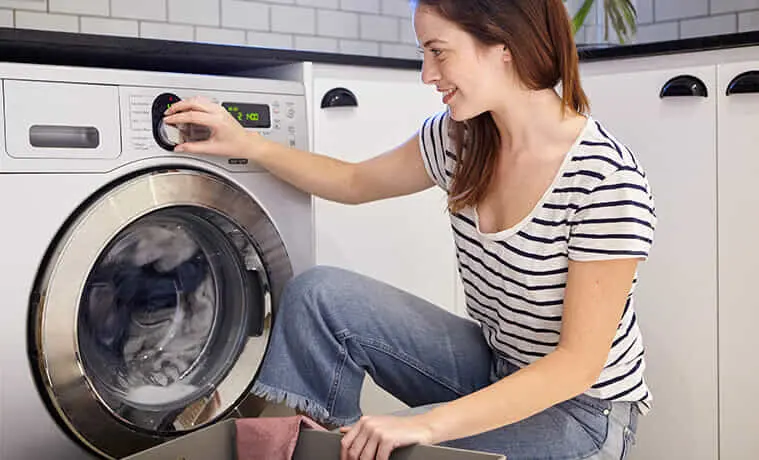 A woman adjusts the settings on her washing machine