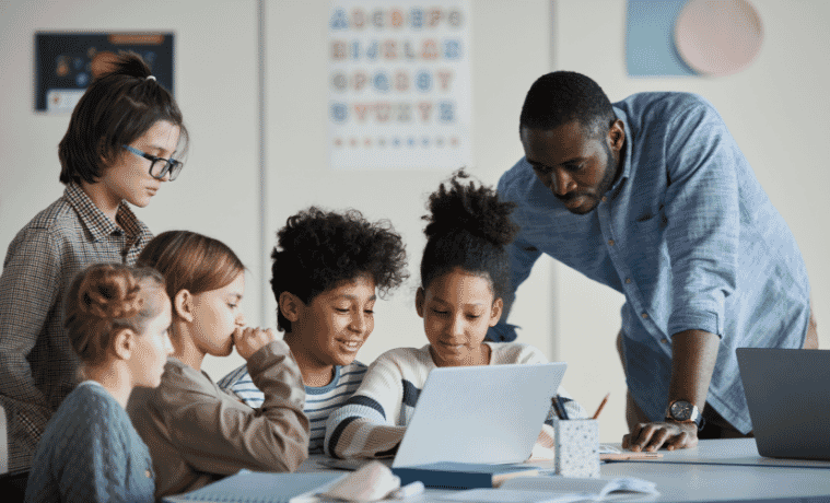 Students and teacher gathered around a 2in1 Laptop