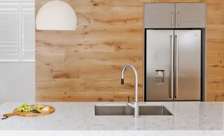 A silver kitchen tap matches the silver kitchen appliances in a timberfilled kitchen