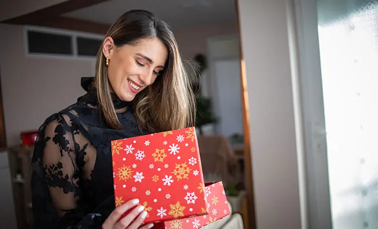 A woman opens a brightly wrapped Christmas present