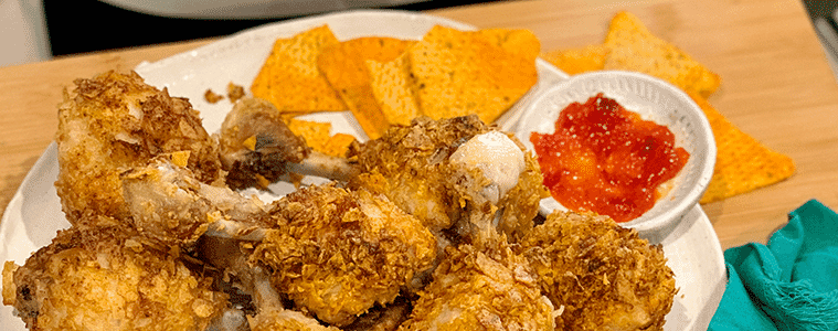 Air fryer chip crusted chicken drumsticks on a white plate with corn chips and potato chips  Image courtesy of Philips