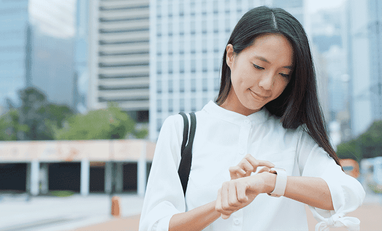 A woman checks her fitness tracker as she goes about her day