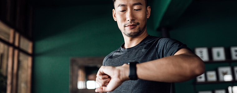 Man exercising at home using a fitness tracker app on his smartwatch to monitor training progress and measure his pulse 