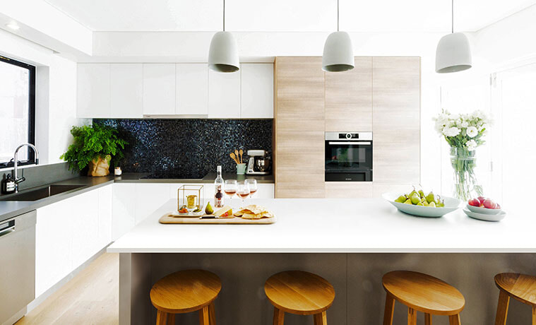 Modern open plan kitchen with chunky wooden stools and timberlook oven feature wall