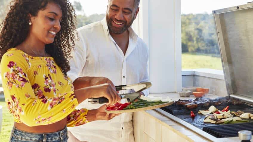 Couple cooking vegetables and meat on their built in BeefEater BBQ 