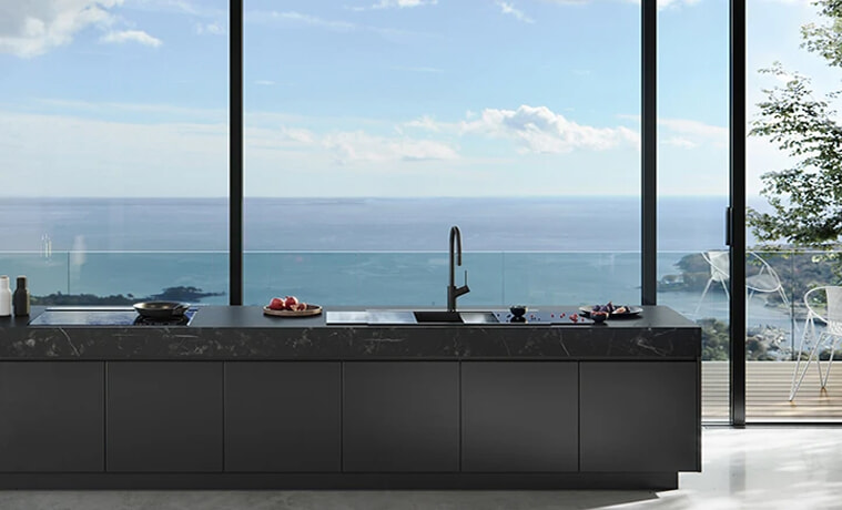 An allblack kitchen with a view of the ocean