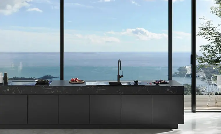 An allblack kitchen with a view of the ocean