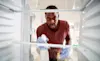 A man sprays and wipes down the interior of his fridge