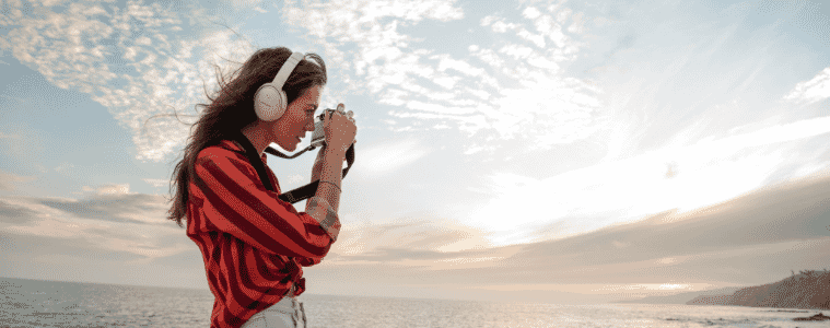 a woman looking out into the ocean listening to music with her noise cancelling Bose headphones