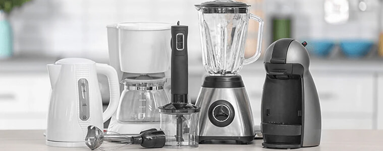 From left to right A white kettle a white coffee pot a black hand blender a chrome blender and a chrome small kitchen appliance