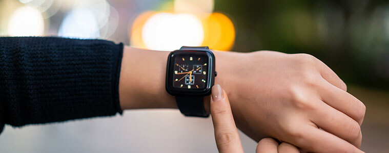 Closeup of a woman holding up her wrist to check the time on her black smartwatch