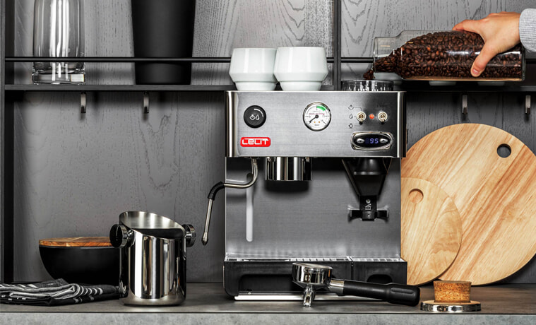 A person refills the grinder on a Lelit Anita coffee machine in a grey kitchen