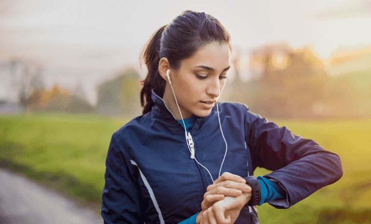 Athletic woman using a smartwatch during her fitness workout on a running path  