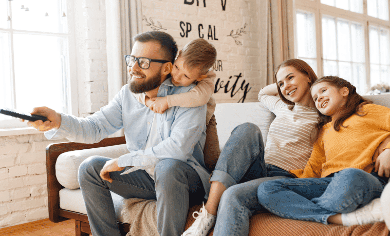 A family sitting on the couch watching TV together 