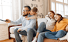 A family sitting on the couch watching TV together 
