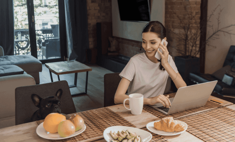 Woman working at desk on the phone next to her dog