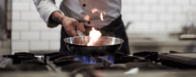 A chef cooks over a gas flame