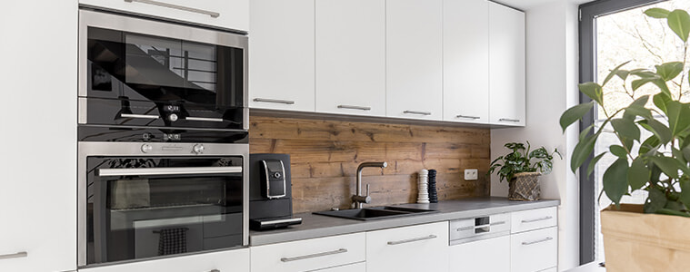 Modern white kitchen with two black wall ovens 