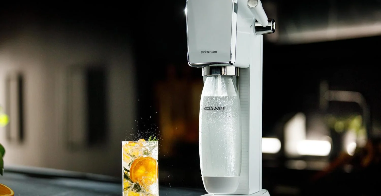 Full length shot of the white ART SodaStream and a fizzy orange beverage
