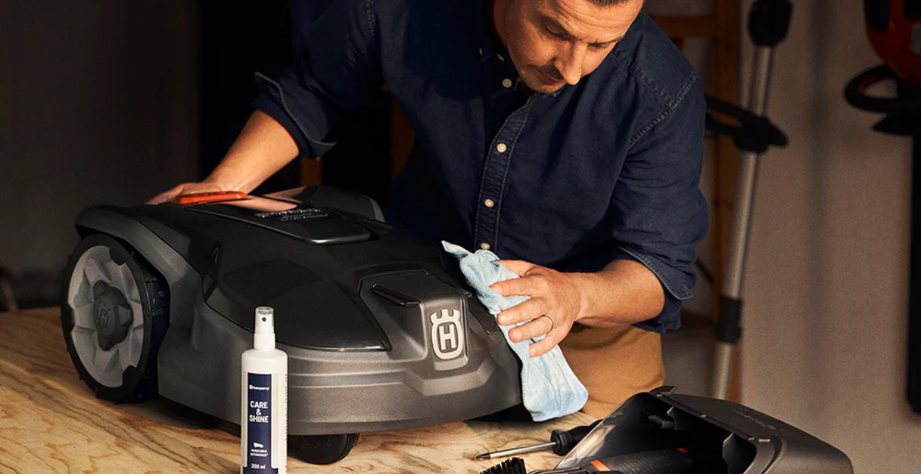 A man cleans his Husqvarna robot lawn mower with a cleaning kit