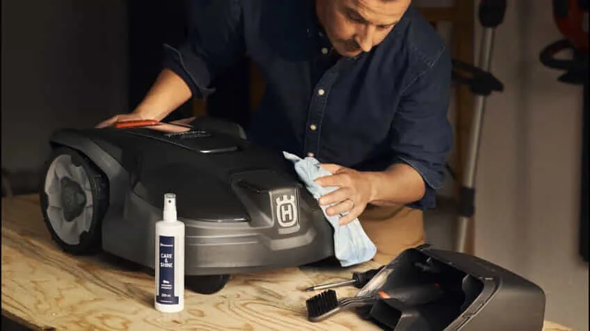A man cleans his Husqvarna robot lawn mower with a cleaning kit