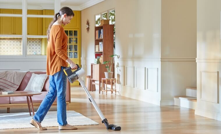 A lady vacuuming her house using the LG handstick vacuum
