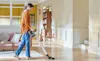 A lady vacuuming her house using the LG handstick vacuum