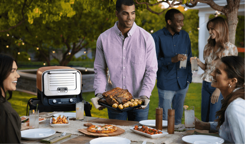 Man serving roast outside from his Ninja Outdoor Oven